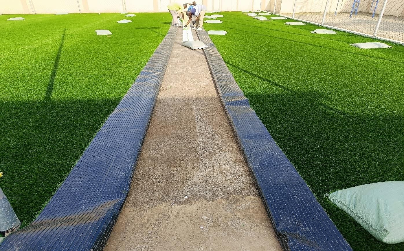 Unrolling artificial turf along the centre seam